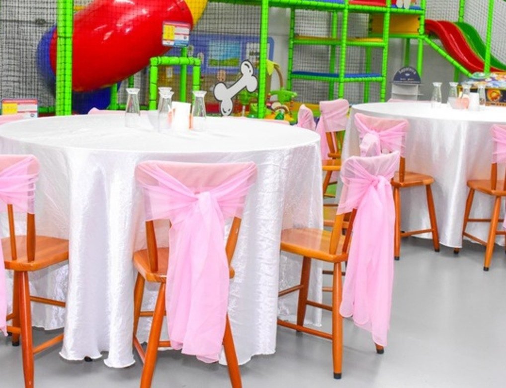 Mesas decoradas com toalha e laços nas cadeiras